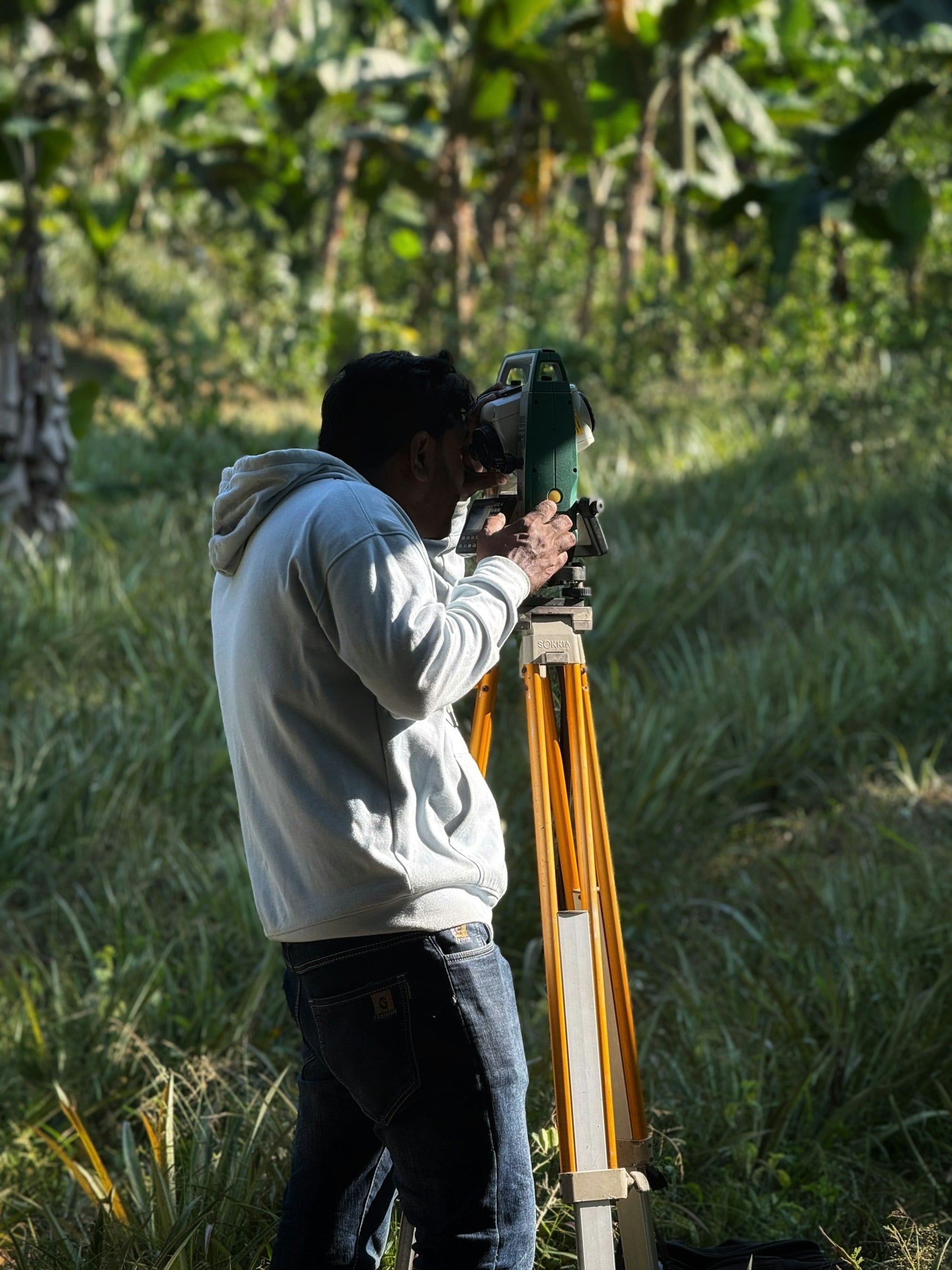 A surveyor measuring a Bangalore plot with a theodolite before design begins.