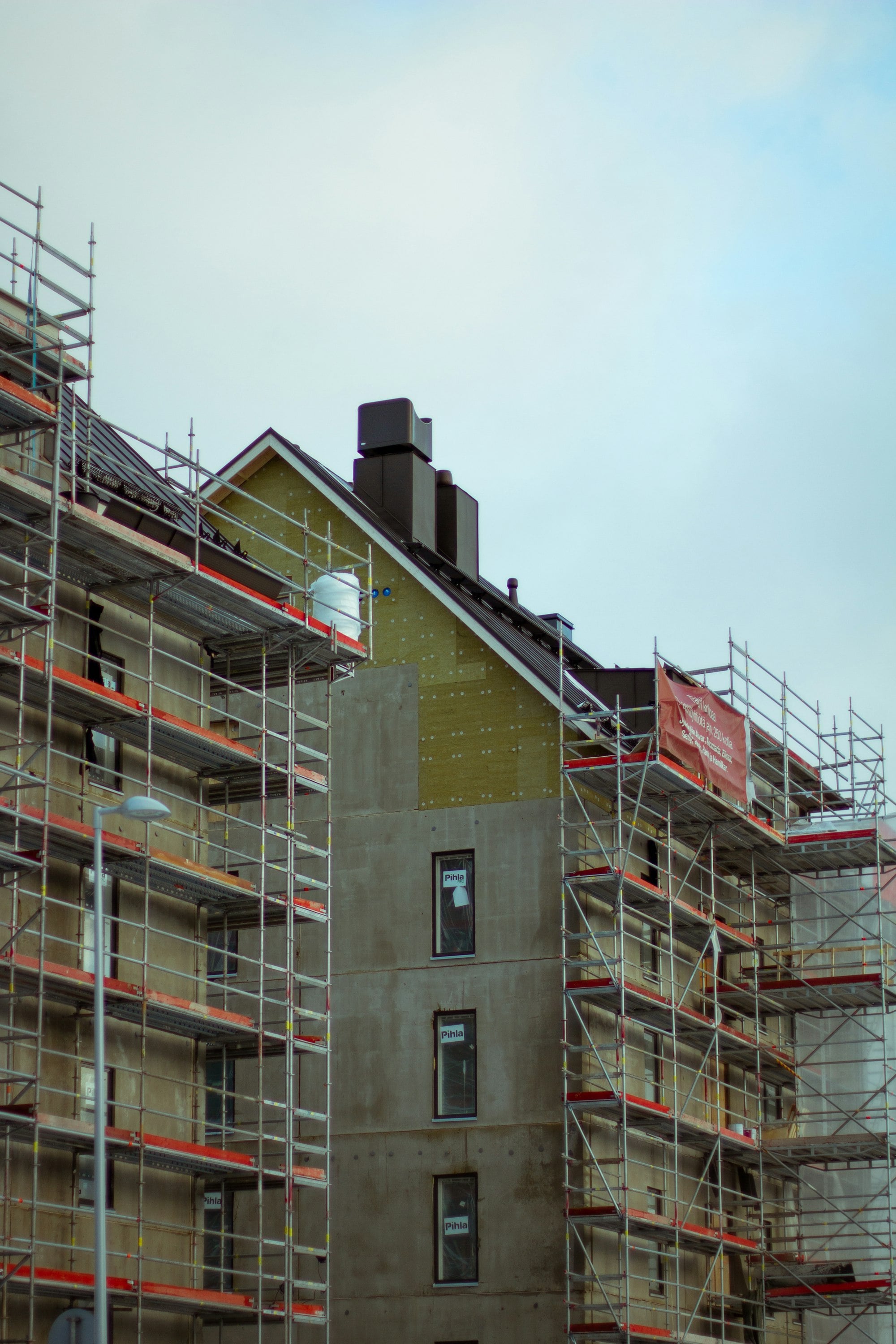 A home under construction — concrete structure and scaffolding rising on site.